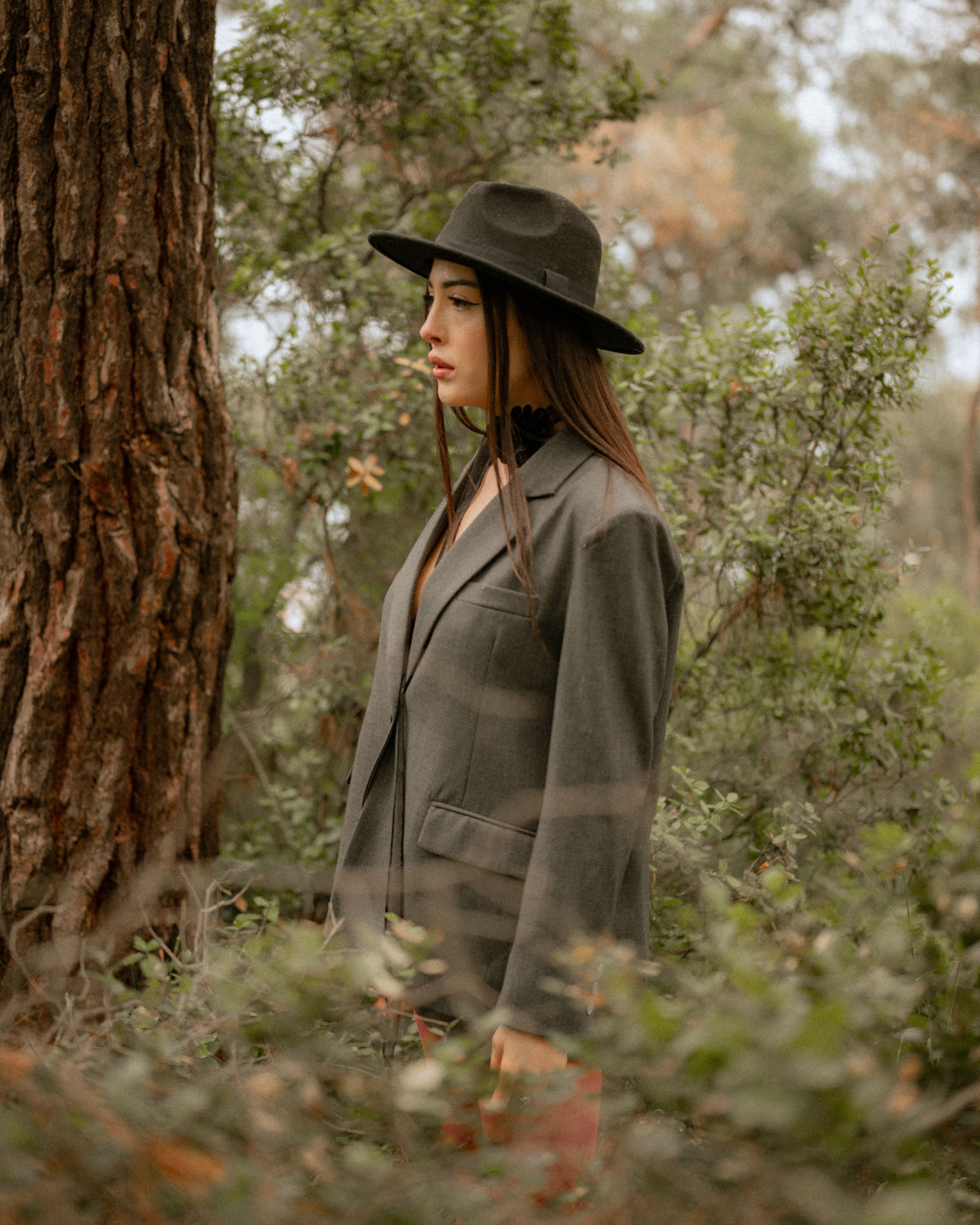 A woman in a hat and jacket standing in the woods · Free Stock Photo