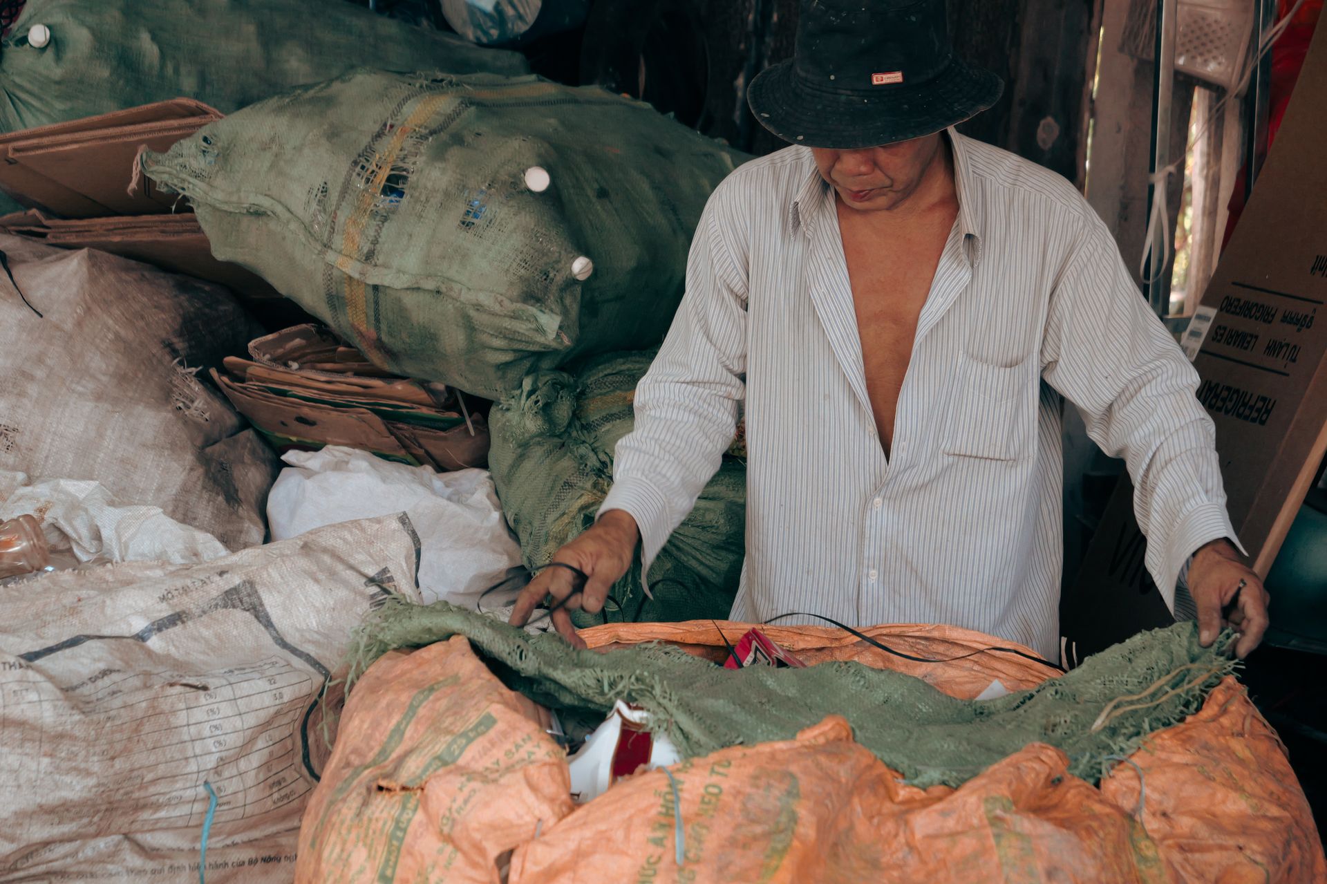 A middle-aged Vietnamese man sorting goods in a bustling Tien Giang market.