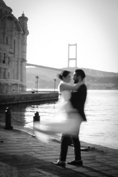 Bride and groom embrace by the Bosphorus Bridge in Istanbul, capturing romantic elegance.