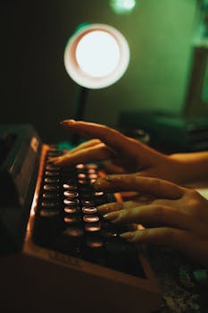 A woman's hands are typing on a vintage typewriter in a dimly lit room, creating a nostalgic atmosphere.