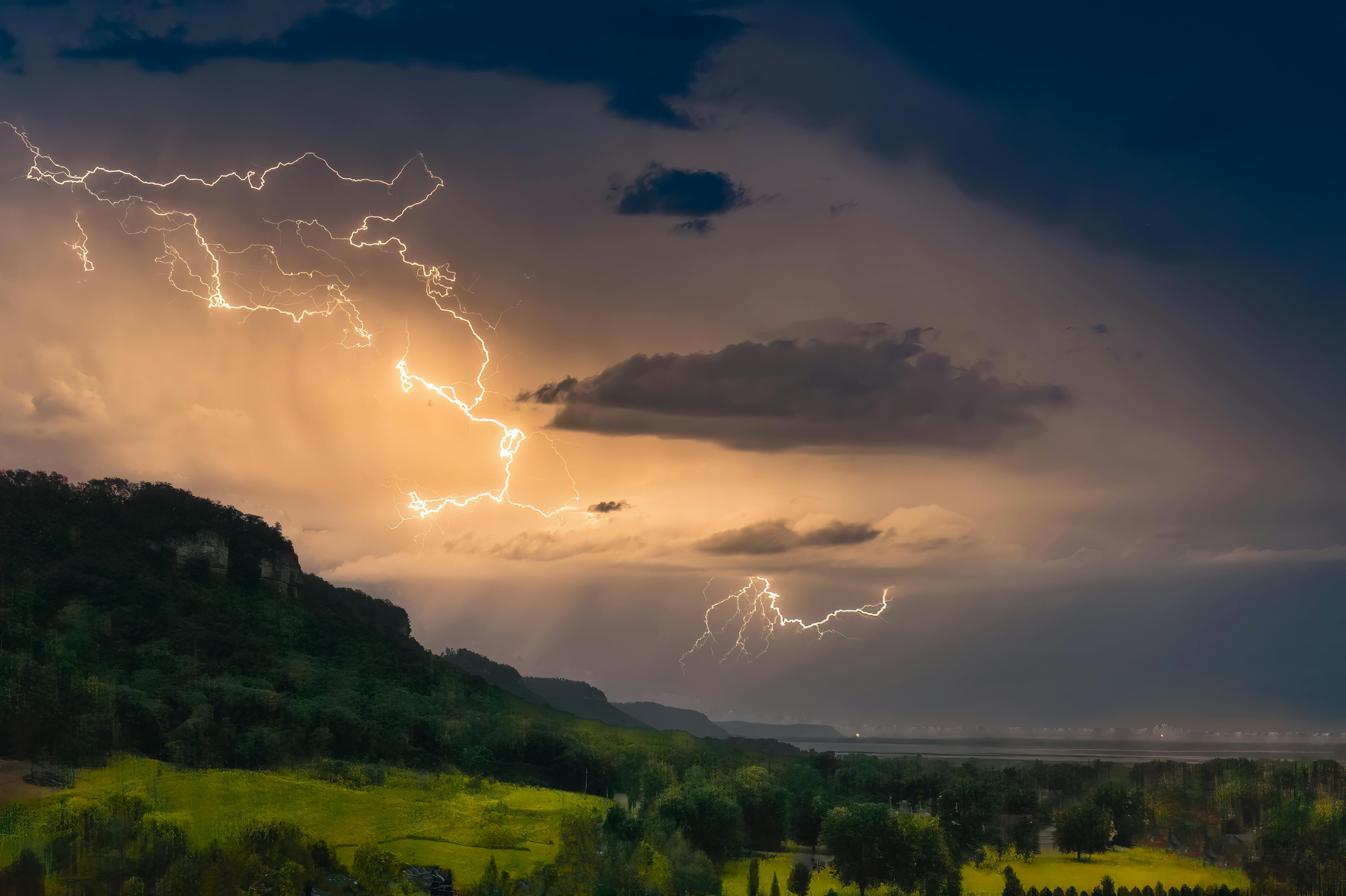 Stunning landscape of a countryside with dramatic lightning striking at dusk, showcasing nature's power.