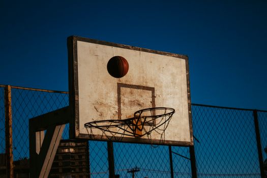 A basketball hoop on a playground during the day with clear blue sky.