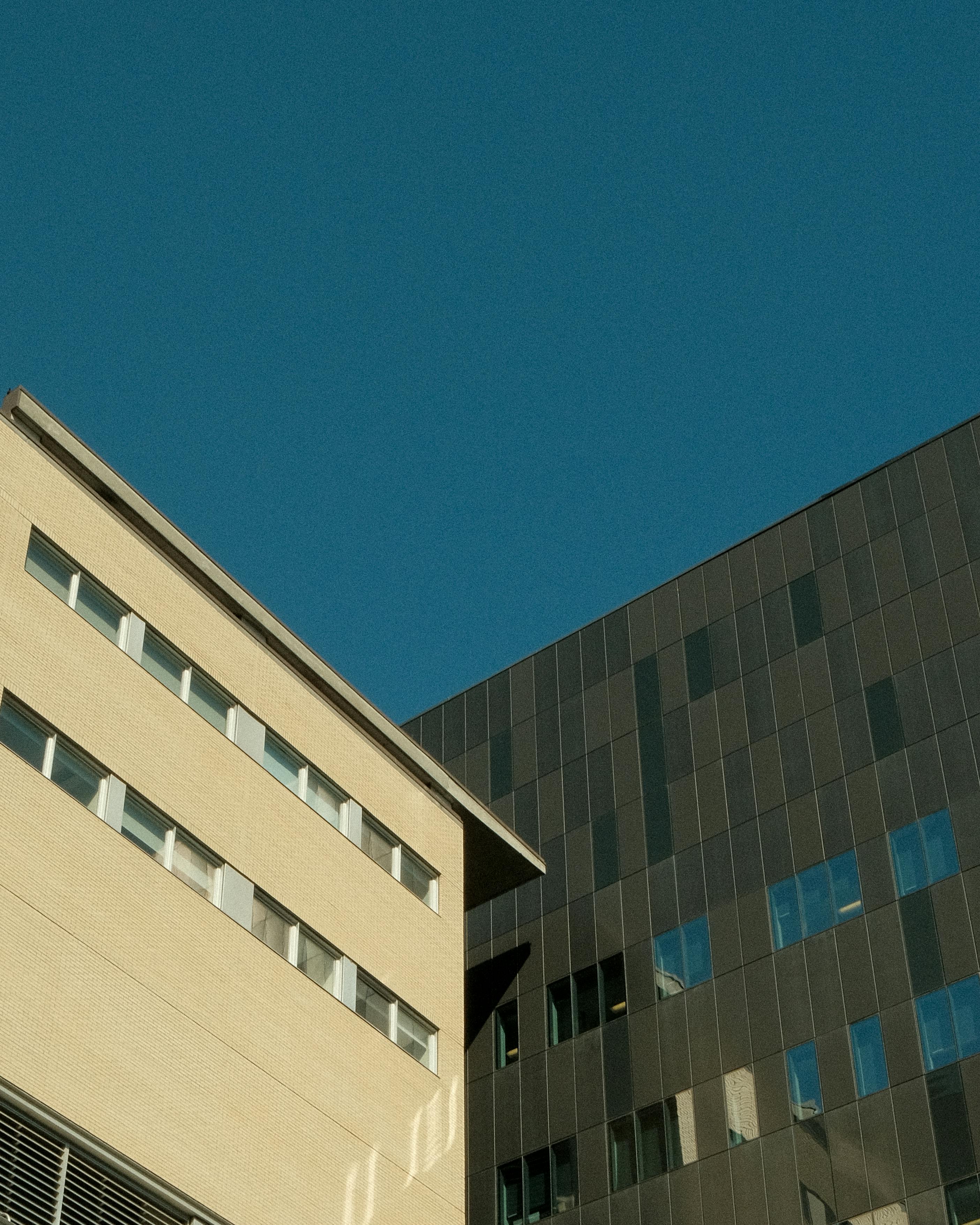 Low angle view of contemporary building facades against clear blue sky