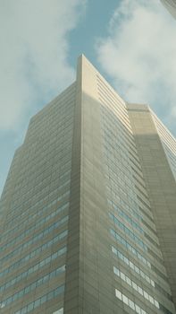 A striking modern skyscraper with reflective glass surfaces reaching into a clear blue sky.