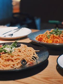 Close-up of spaghetti dishes with vegetables on a restaurant table.