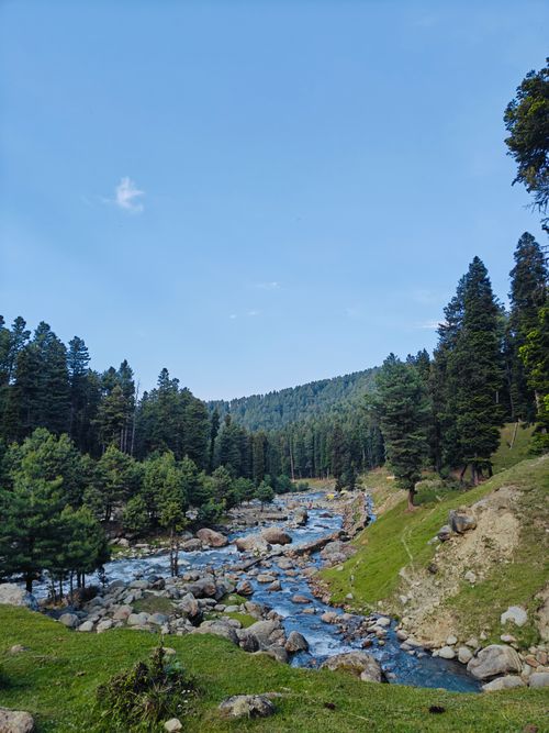 Free Discover the serene beauty of Charar-i-Sharief with this captivating river scene amidst lush greenery and mountains. Stock Photo