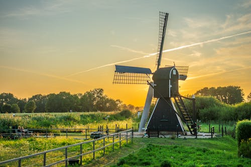 Free Black and White Wind Mill in Green Field Under Yellow Skies Stock Photo