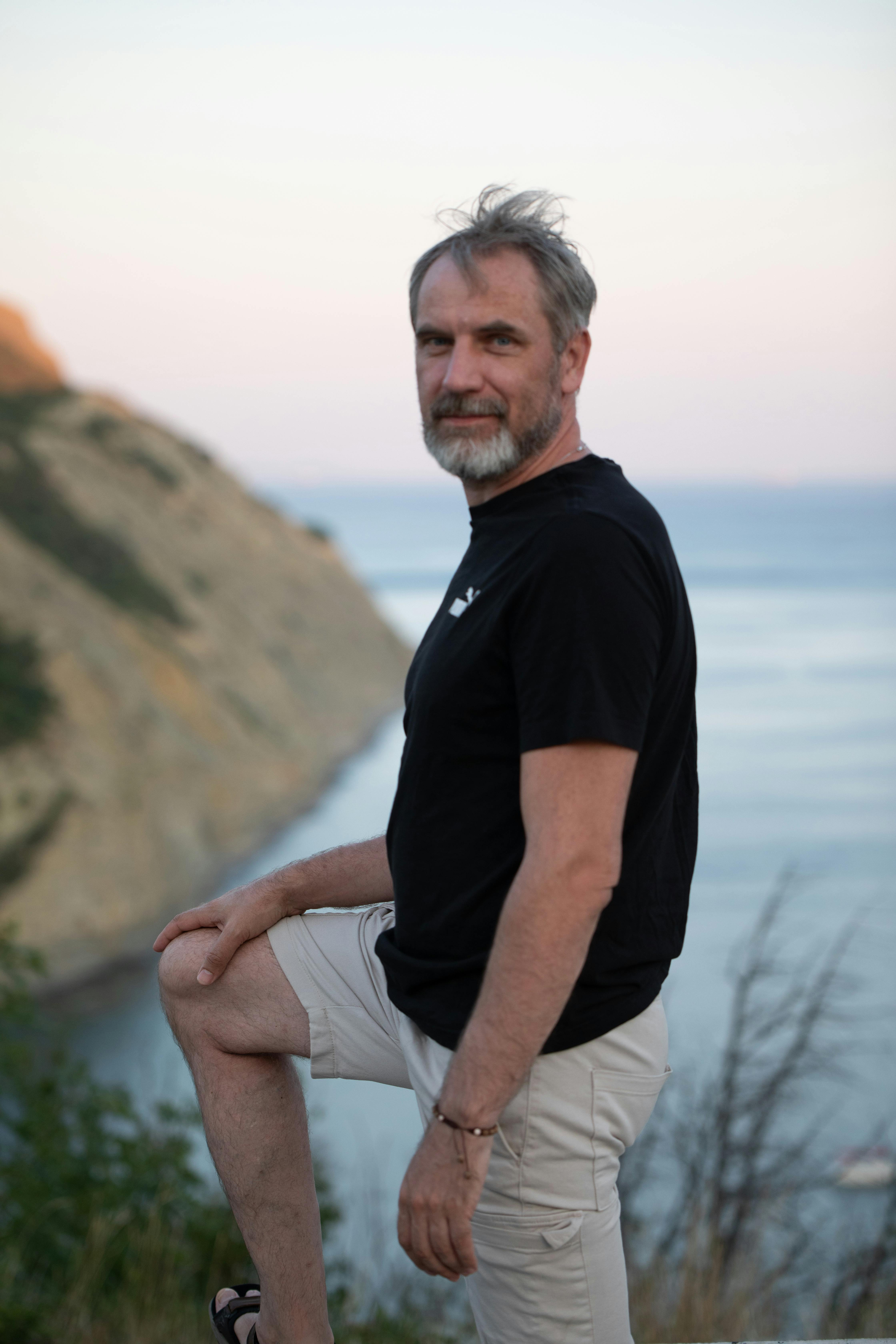 a man in black shirt and shorts sitting on a rock