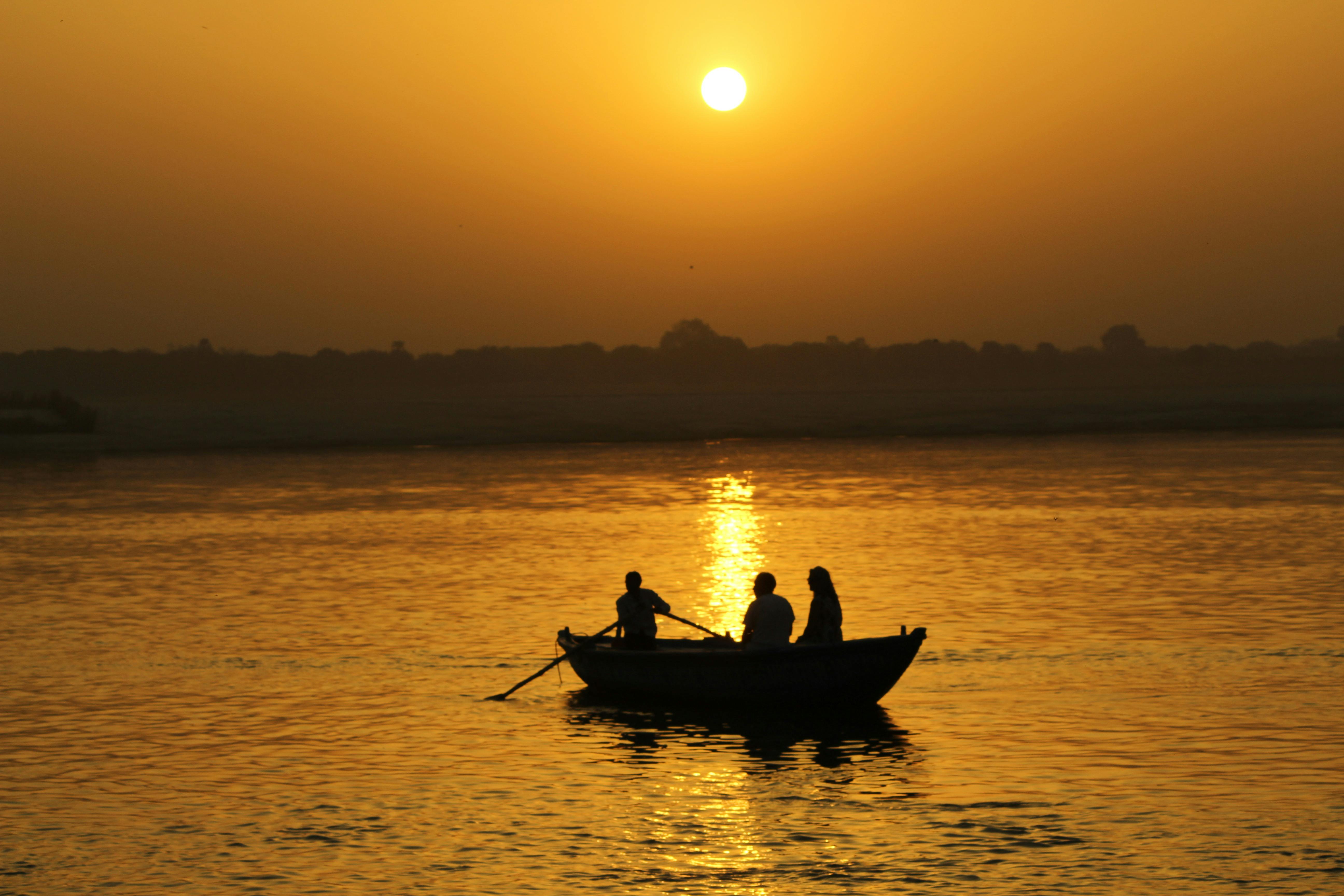 Free Two people in a boat at sunset on the river Stock Photo
