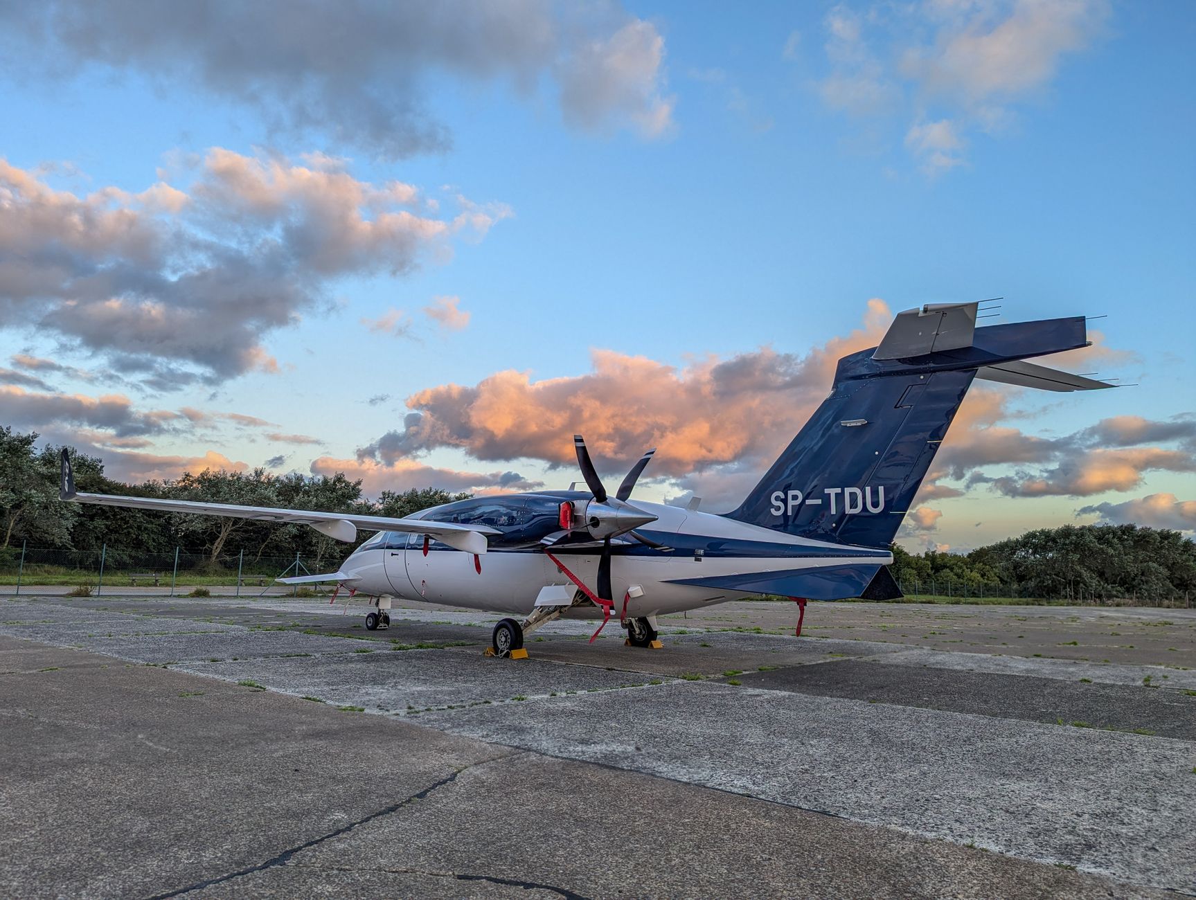 A small aircraft with visible registration parked on the runway at sunset, showcasing a serene aviation scene.