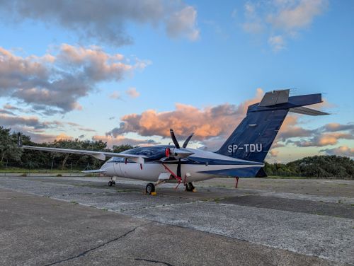 Free A small aircraft with visible registration parked on the runway at sunset, showcasing a serene aviation scene. Stock Photo