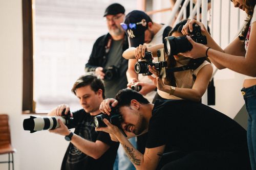 Free Multiple photographers with cameras taking shots indoors. Team of diverse ages and genders. Stock Photo