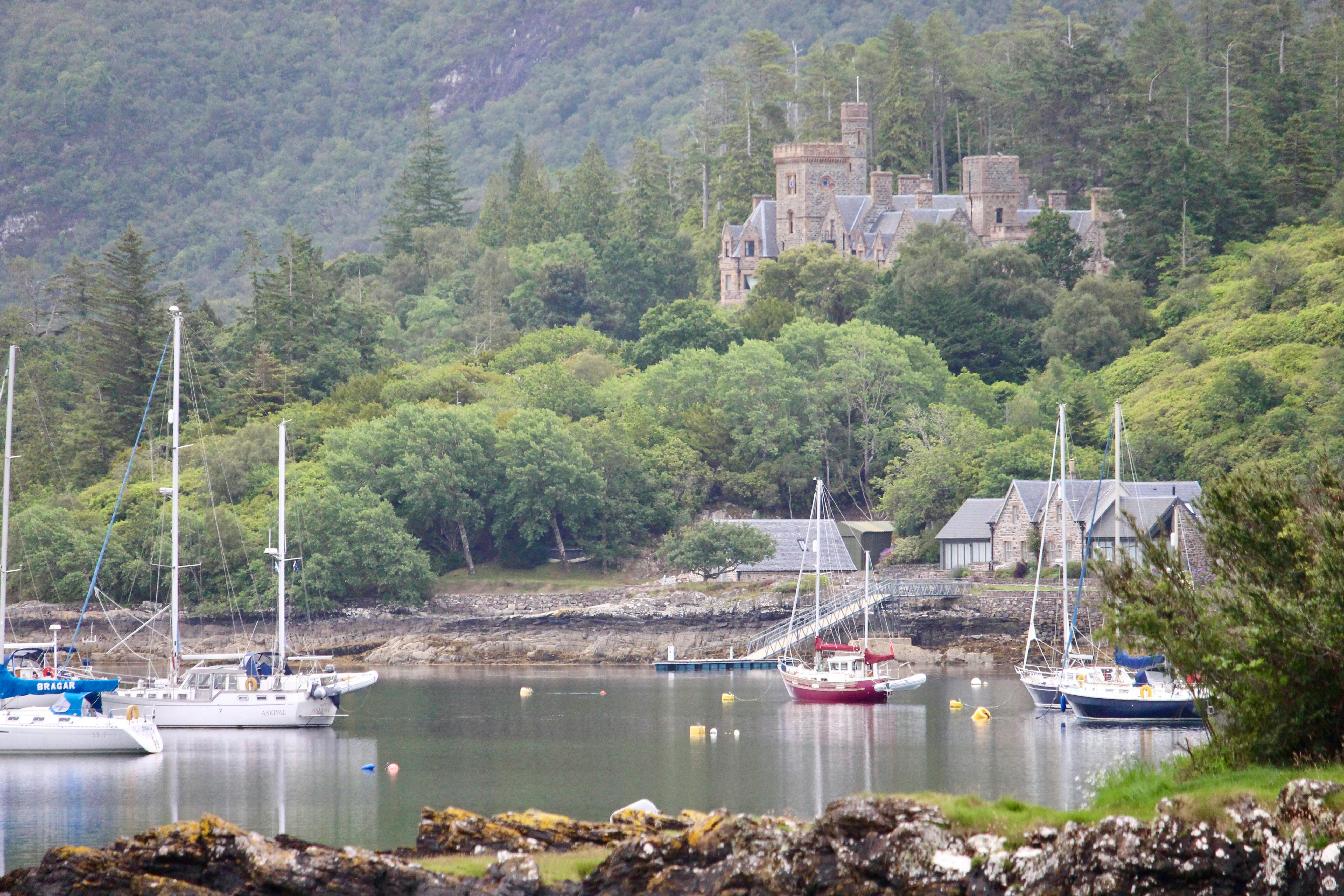 Charming lake view with a historic castle and boats surrounded by lush greenery.