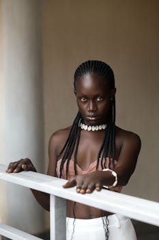 Striking portrait of a woman in Kumasi, Ghana, showcasing braided hair and fashion accessories.
