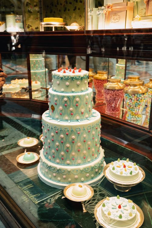 Free Elegant blue three-tier cake with intricate designs in a Milano bakery window display. Stock Photo