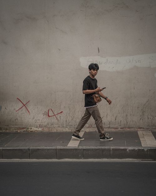 Free Young man walking on a street with graffiti in İstanbul. Capturing urban life and motion. Stock Photo