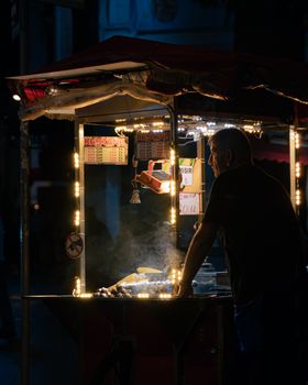 A street vendor in Istanbul selling roasted chestnuts at night under decorative lights.