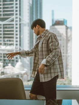 A young man in casual office attire in a modern high-rise setting.