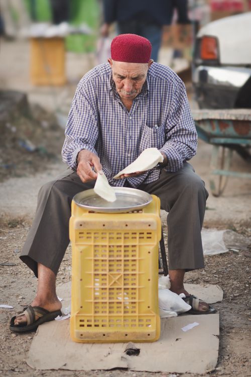 Free A senior man prepares traditional malsouka in a Tunisian street market, showcasing cultural cuisine. Stock Photo