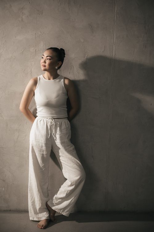 Free An elegant fashion portrait of a young woman posing against a textured concrete wall in a studio setting. Stock Photo