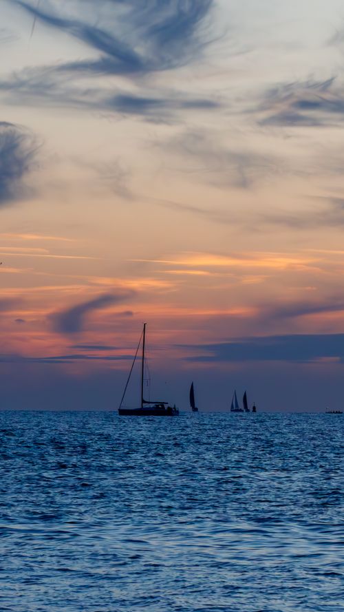 Free Serene ocean view at sunset with sailboats on the horizon, capturing nature's beauty. Stock Photo