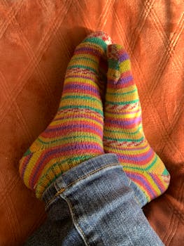 Colorful knit socks on a cozy orange background, creating a warm autumn vibe.