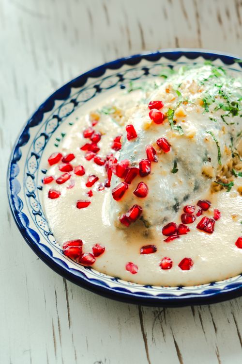 Free Traditional Mexican dish featuring creamy sauce and pomegranate seeds on a decorated plate. Stock Photo