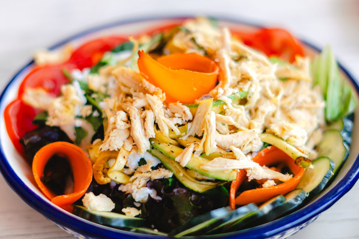 Shredded chicken salad bowl with tomatoes and zucchini