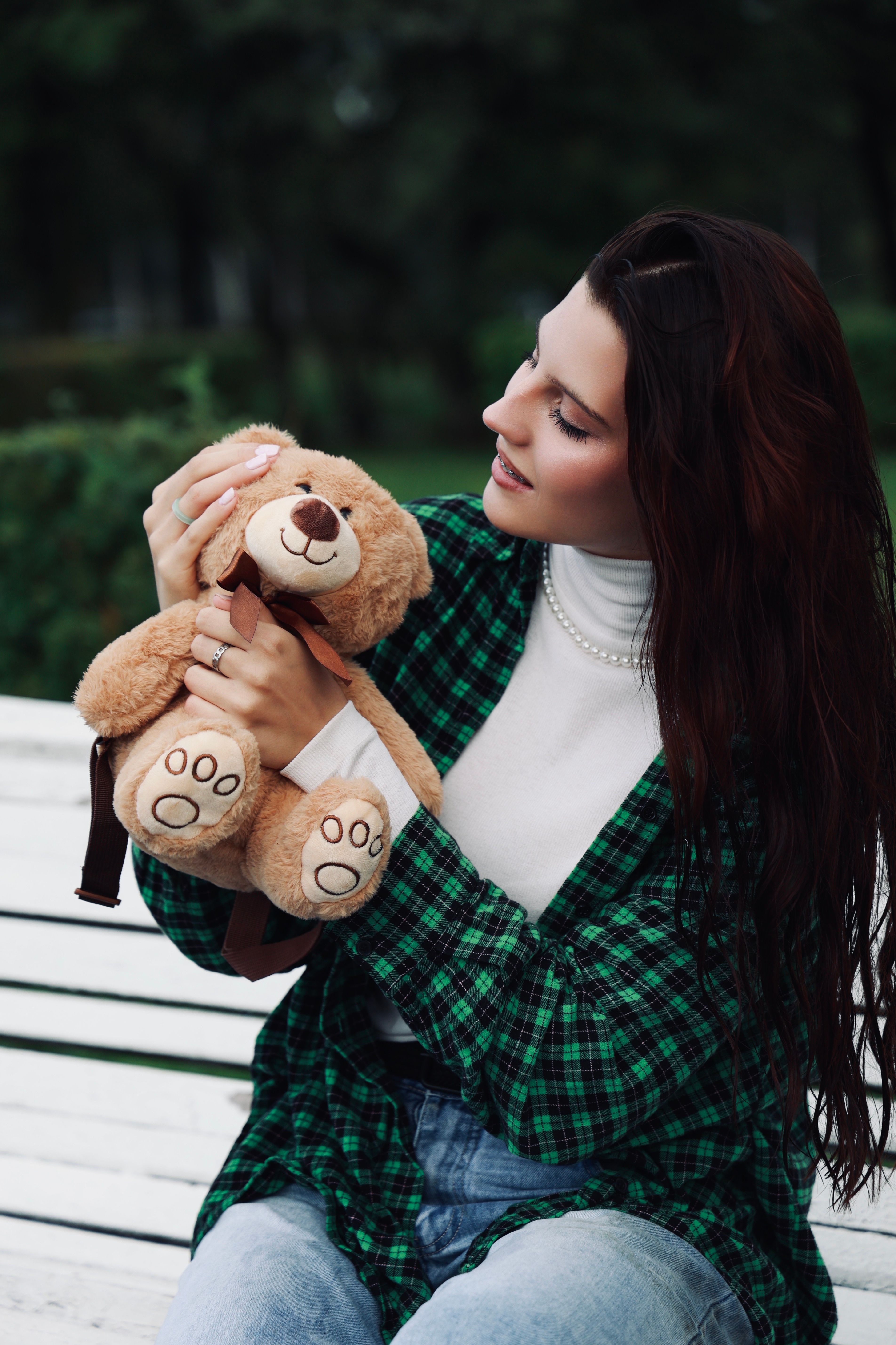 A woman holding a teddy bear on a bench · Free Stock Photo