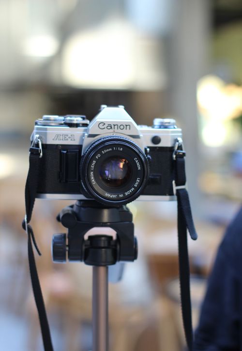 Free Close-up of a vintage Canon AE-1 camera mounted on a tripod indoors. Stock Photo