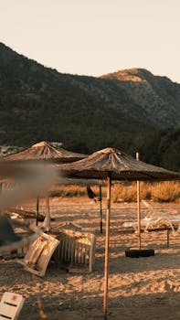 Serene beach view with straw umbrellas at sunset, ideal for relaxation and vacation.