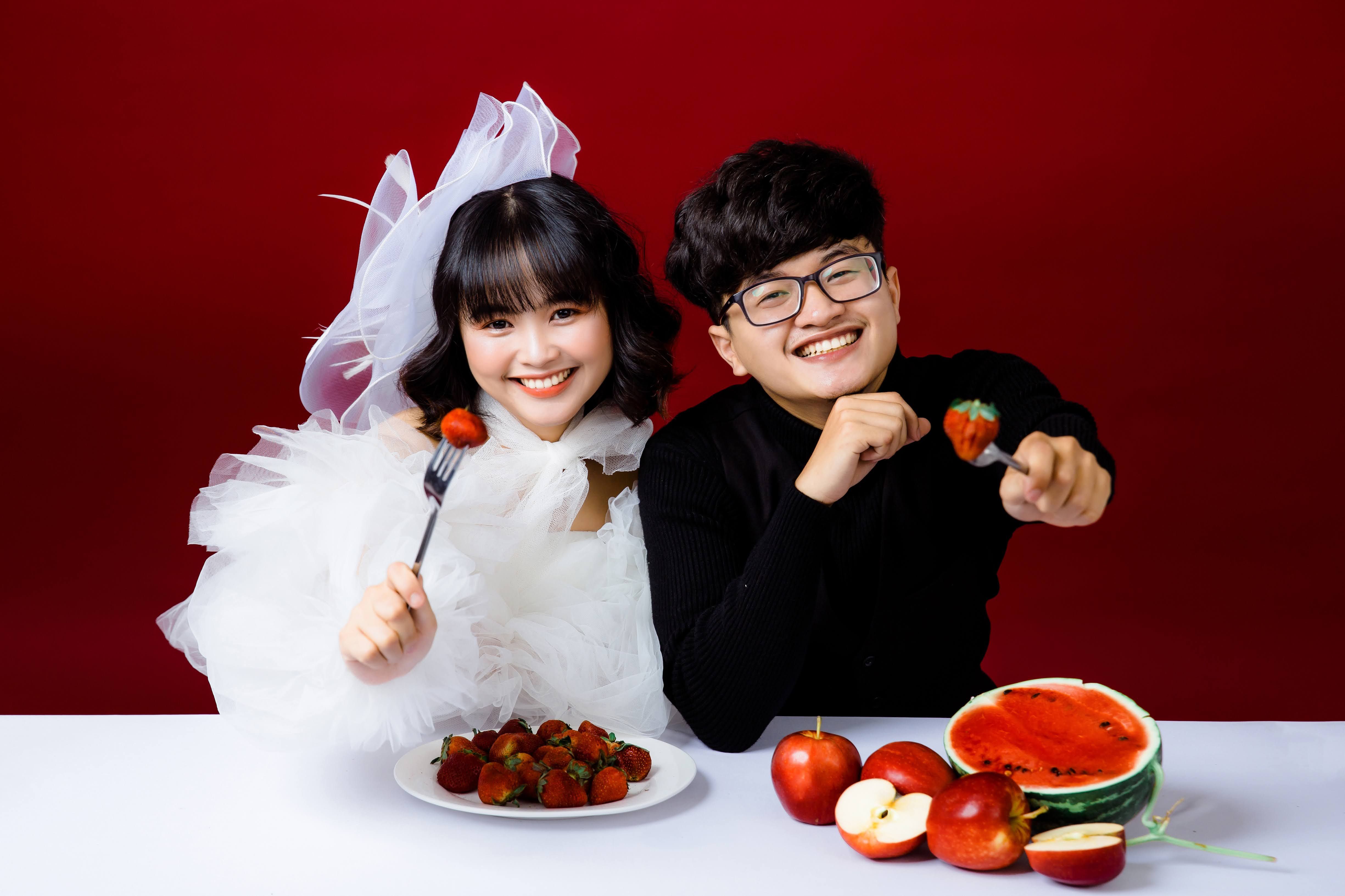 Free Happy couple enjoying a moment with strawberries and watermelon in a vibrant studio setting. Stock Photo