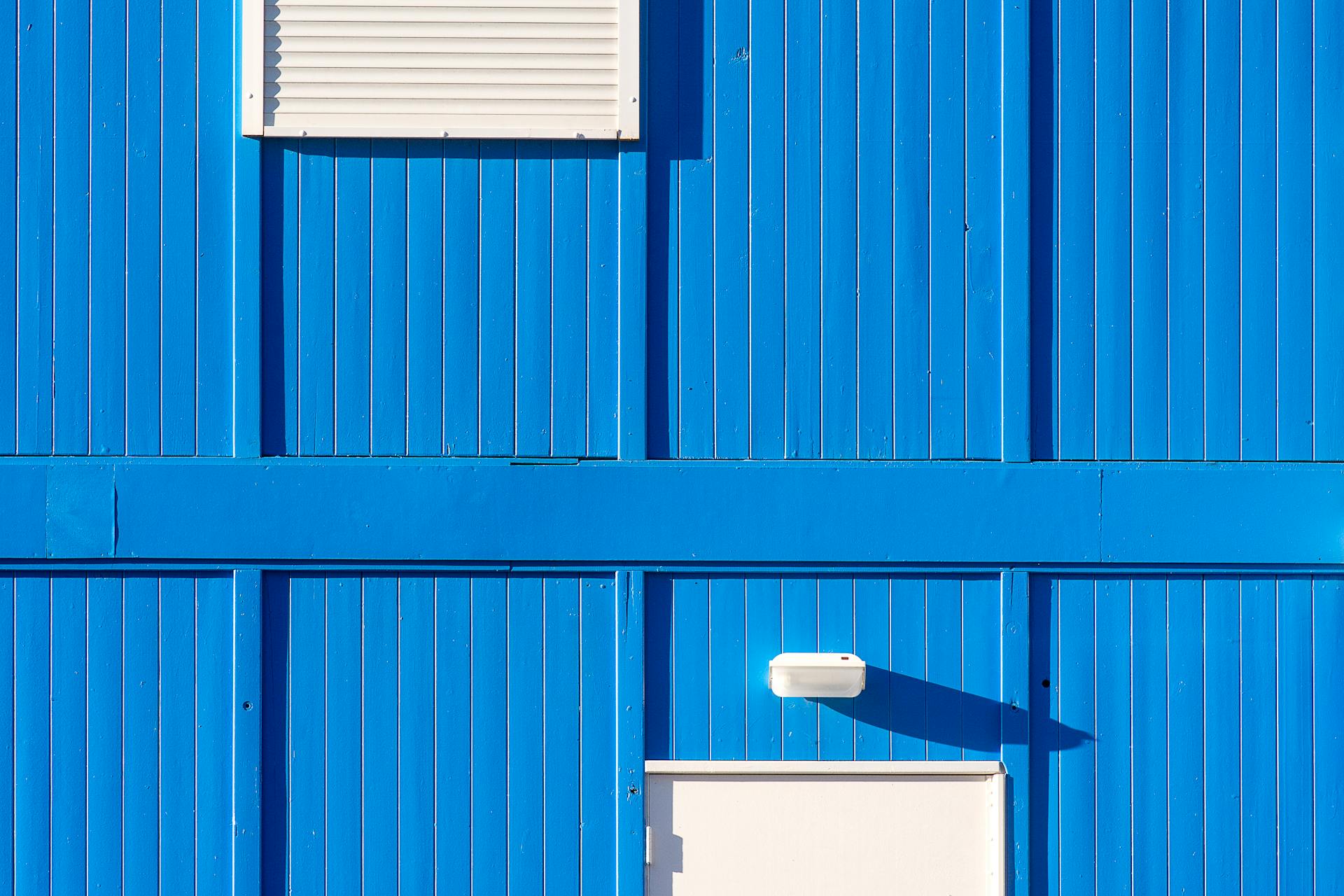 A blue building with white shutters and a blue roof