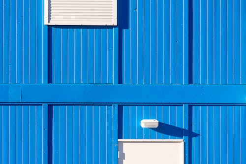 Free Minimalist blue corrugated exterior wall with a window. Ideal for design and architecture concepts. Stock Photo