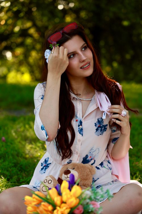 Free A woman enjoys a sunny day in a park, surrounded by vibrant flowers and nature. Stock Photo
