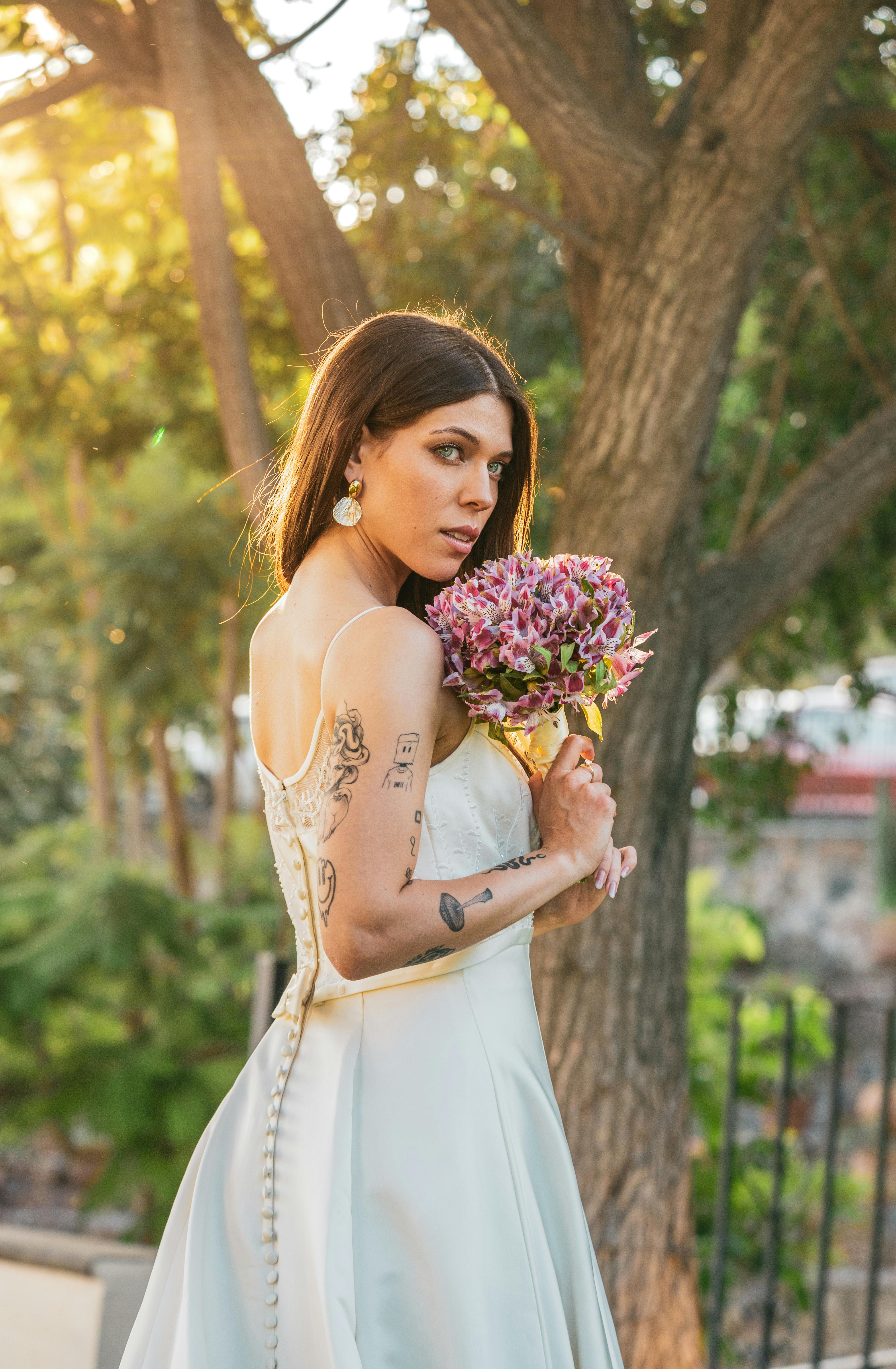 A bride holding a bouquet under warm sunlight in a lush garden.