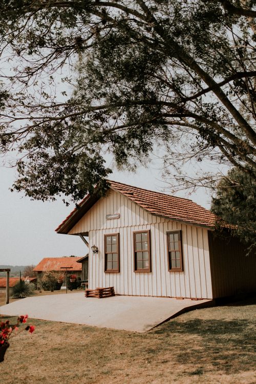 Free Rustic wooden cottage surrounded by trees in a serene countryside setting, perfect for travel inspiration. Stock Photo