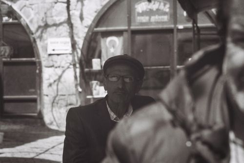 Free Black and white portrait of an elderly man captured on a street, showcasing timeless expression and atmosphere. Stock Photo