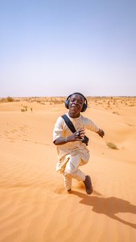 Man expressing happiness in a vast desert landscape on a sunny day.