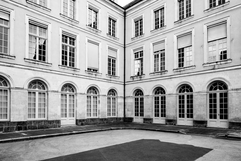 Monochrome view of a classic French courtyard with arched windows and vintage facade.