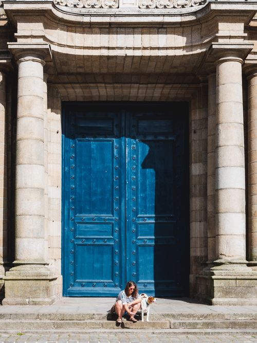 Free Traveler with dog at a grand blue doorway in Rennes, France, showcasing historic architecture under a clear sky. Stock Photo