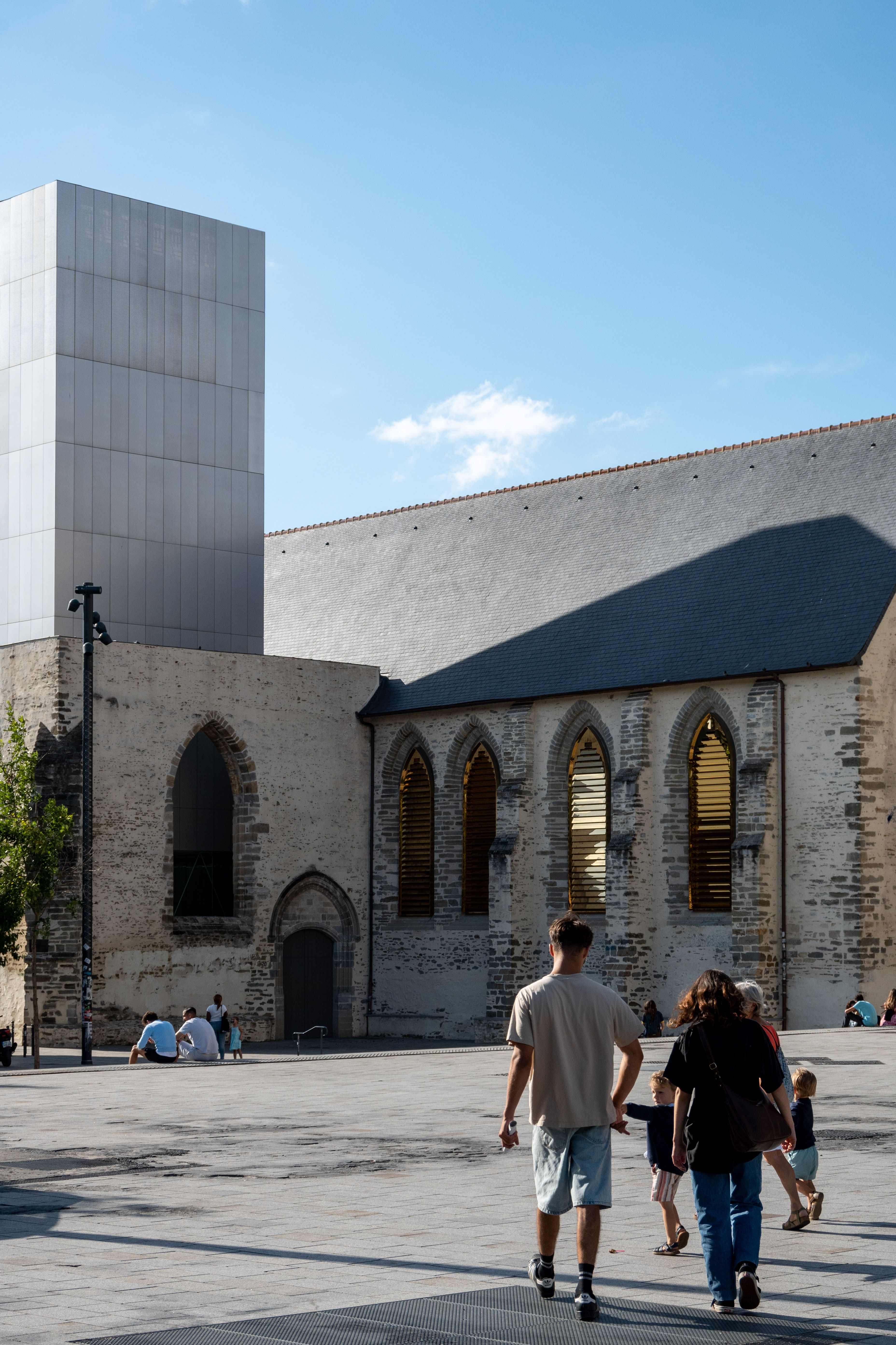 People walking near modern architecture in Rennes, Brittany, blending history and urban life.