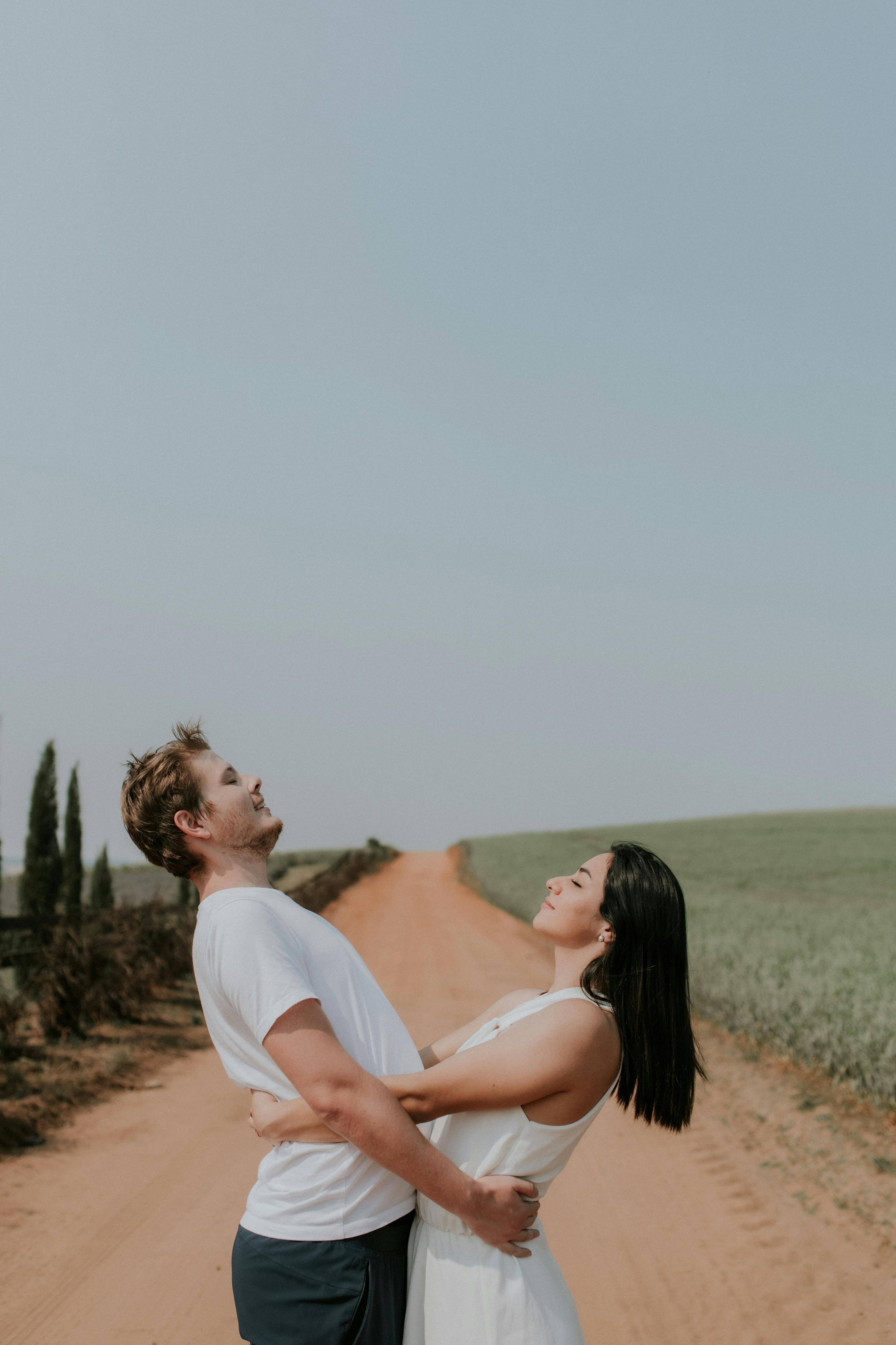 a couple embracing on a dirt road in the middle of a field