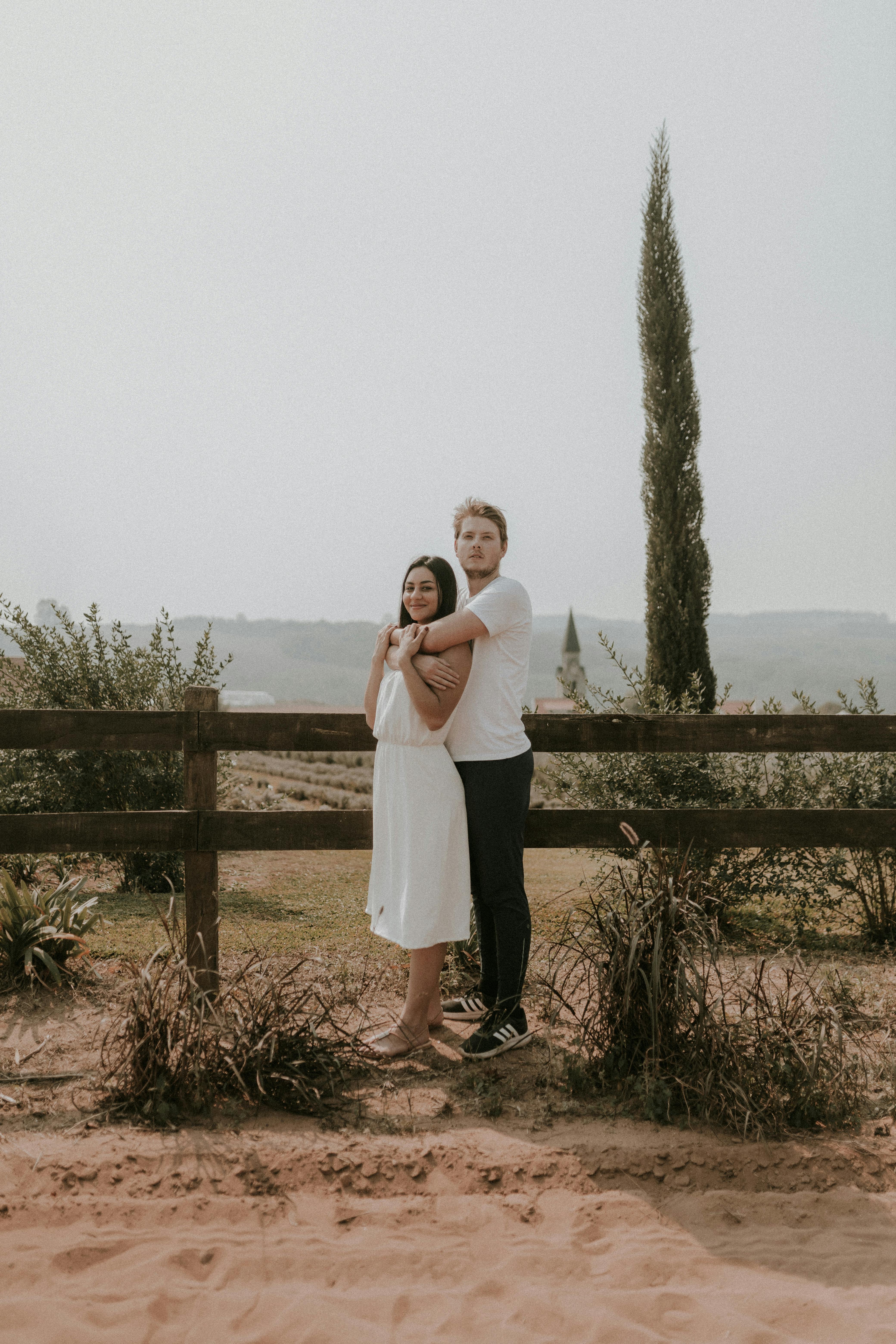 a couple standing in front of a fence