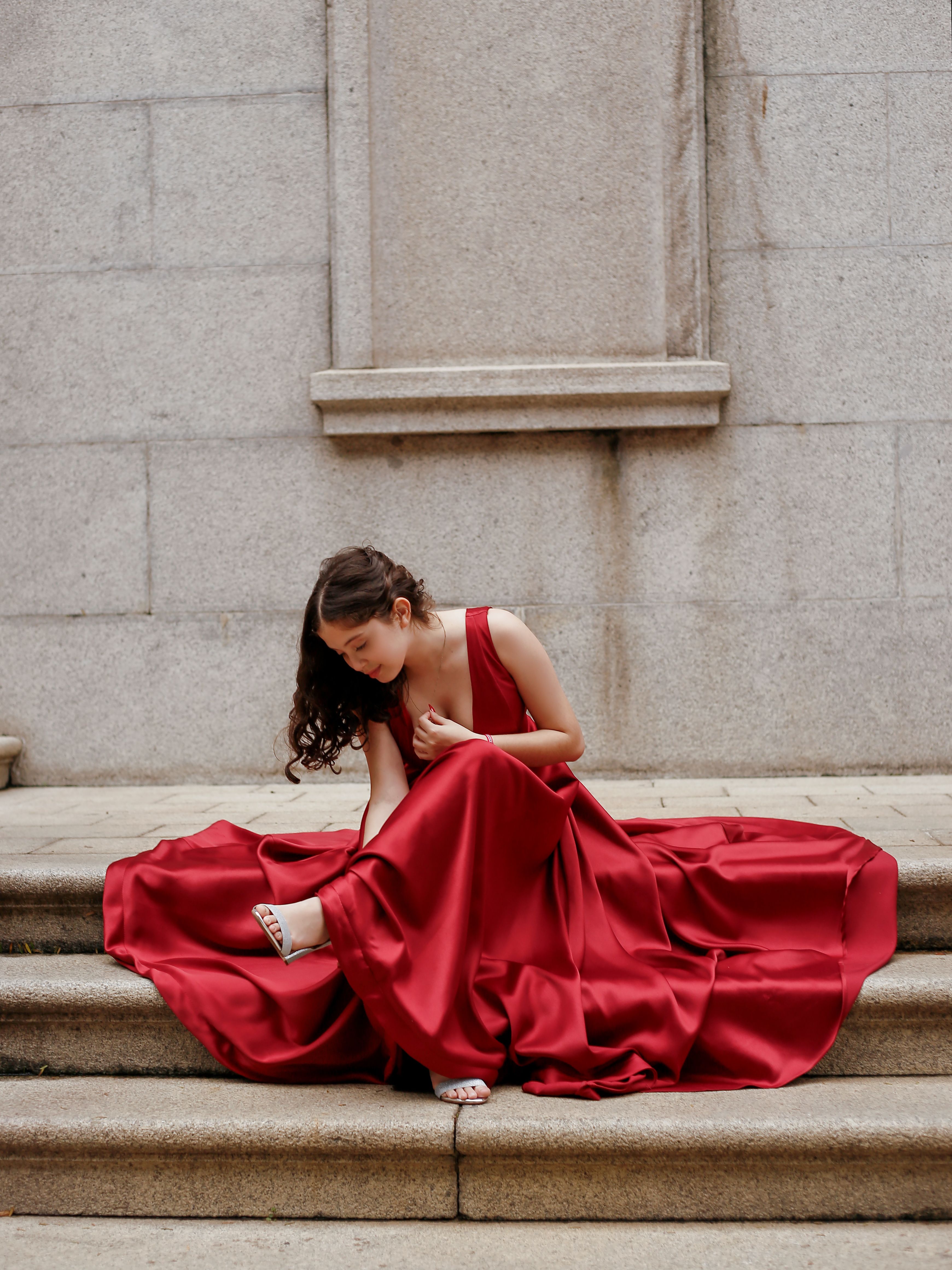 A woman in a red dress sitting on some steps · Free Stock Photo
