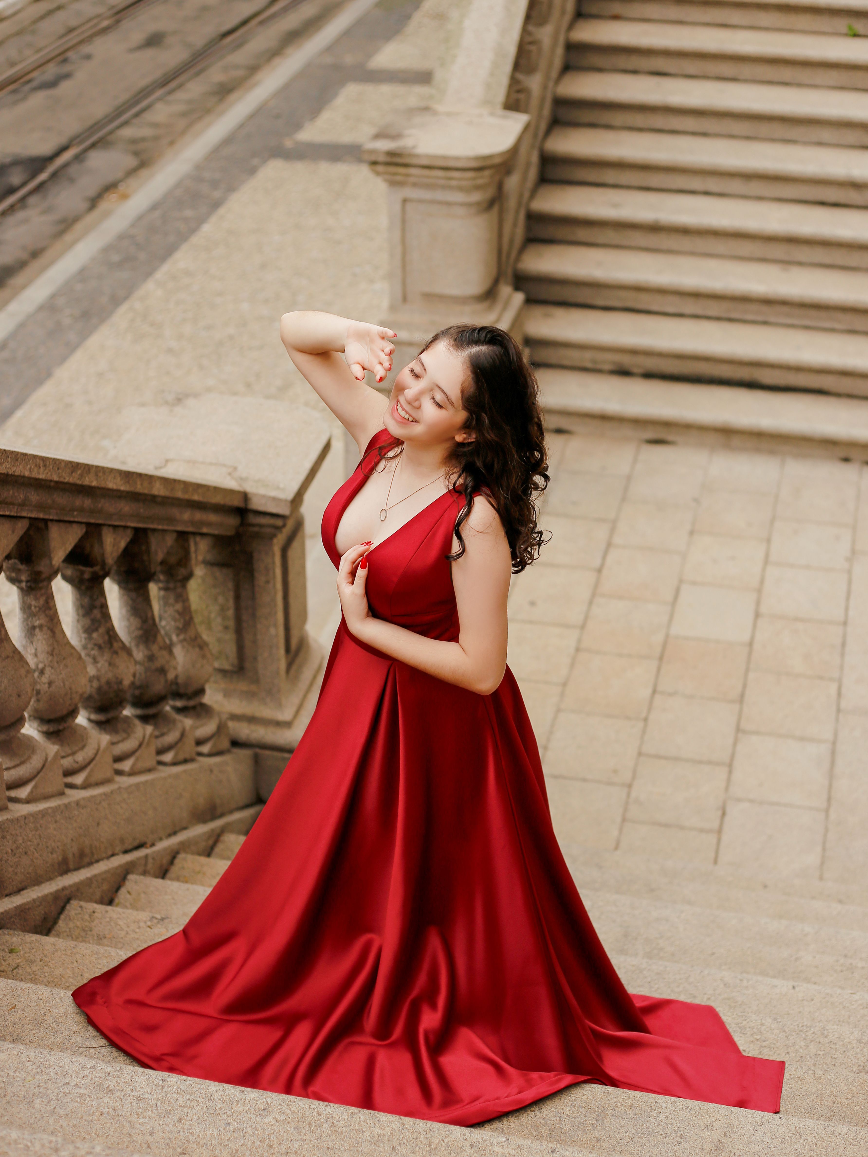 A woman in a red dress is posing on some stairs · Free Stock Photo