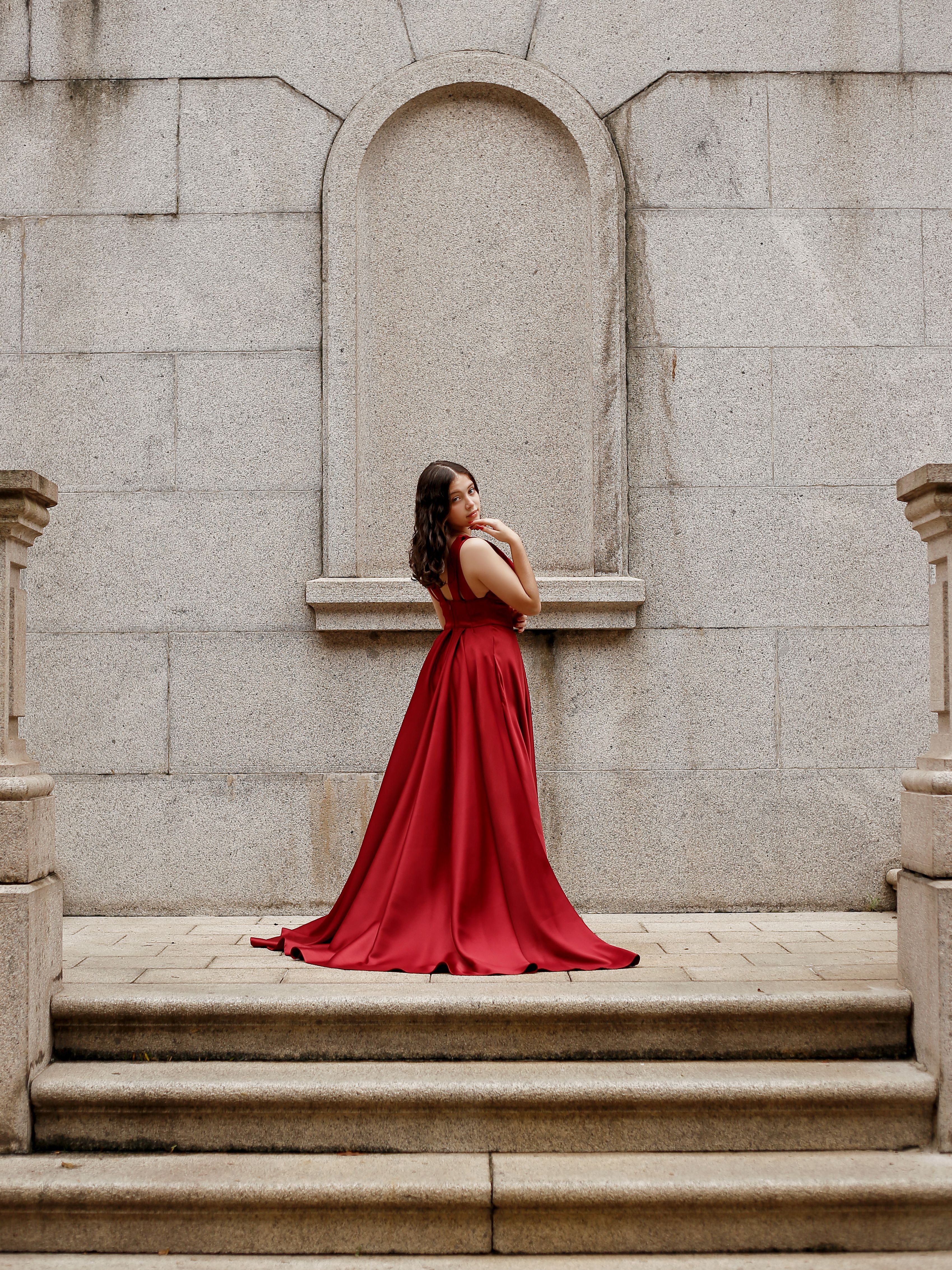 Editorial image of a red formal gown on stone steps