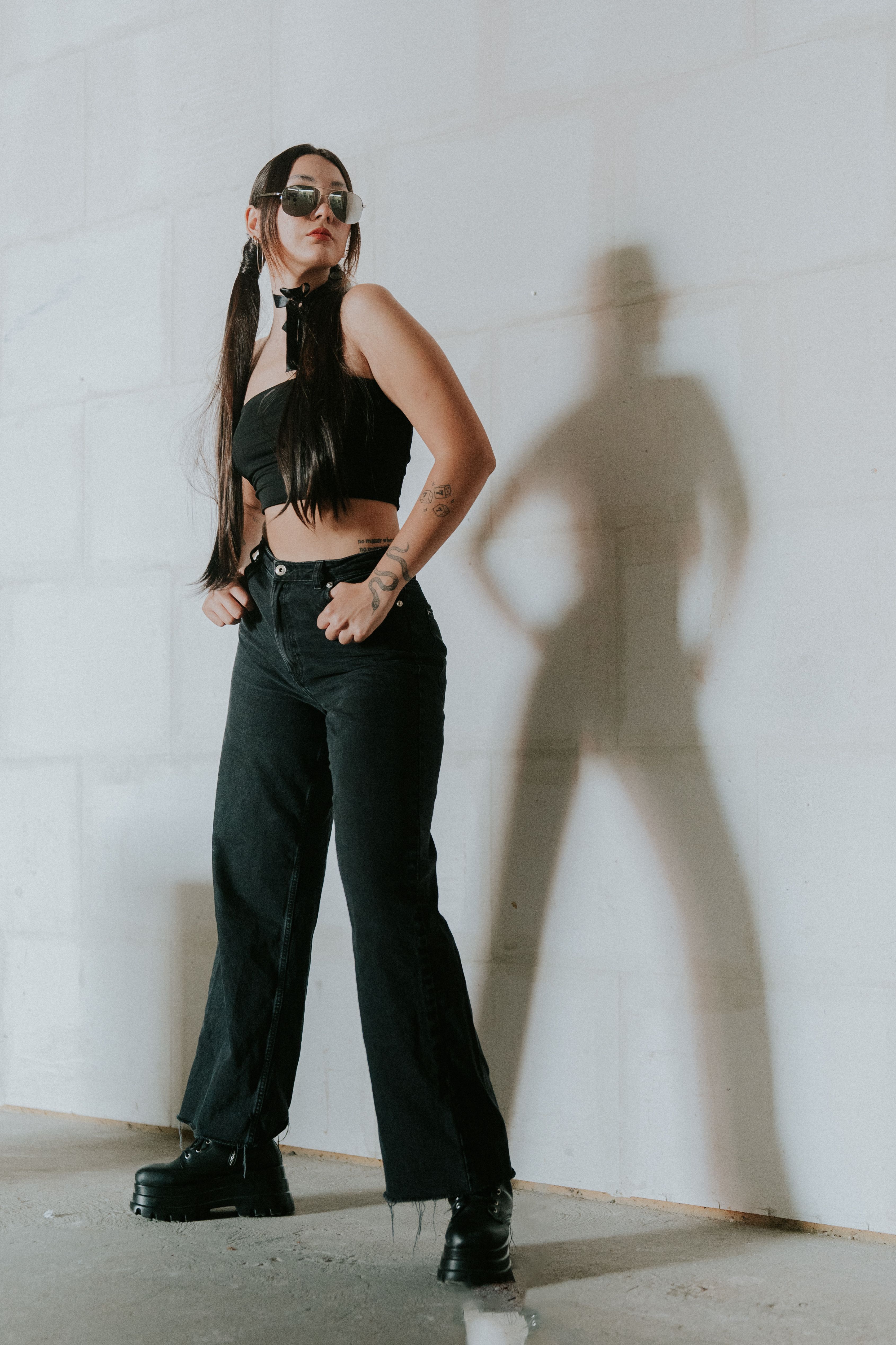 A woman in black pants and a top standing in front of a wall · Free ...