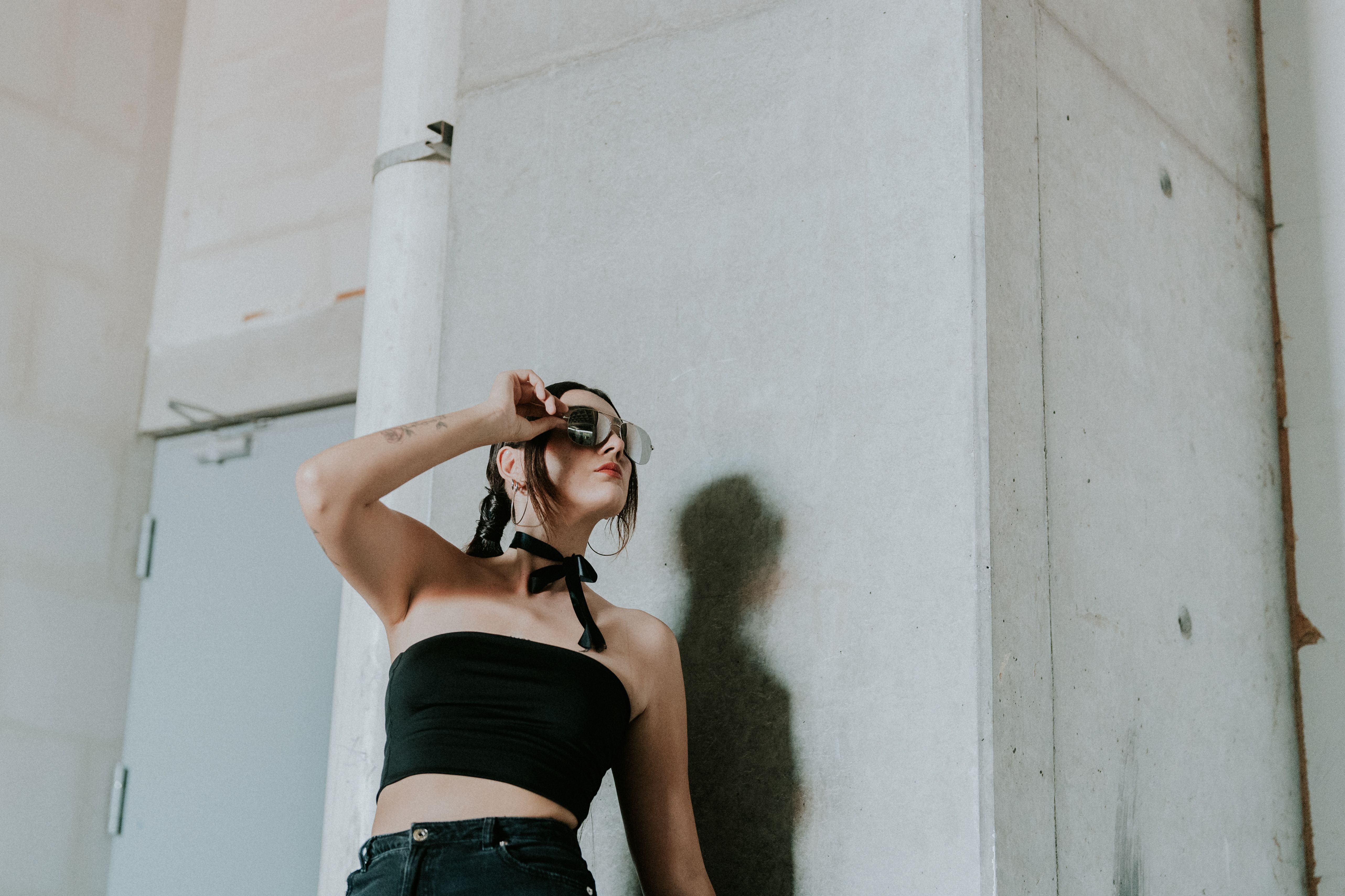 A woman in black pants and a crop top is leaning against a wall · Free ...