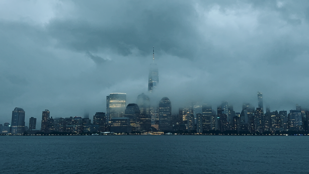 Dark and dramatic view of New York City skyline shrouded in fog, highlighting its skyscrapers.